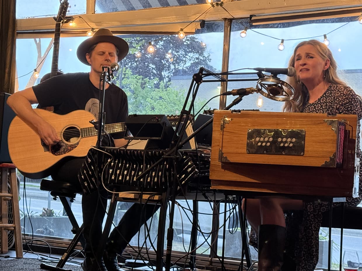 Lisa at the harmonium and David on guitar, playing under string lights