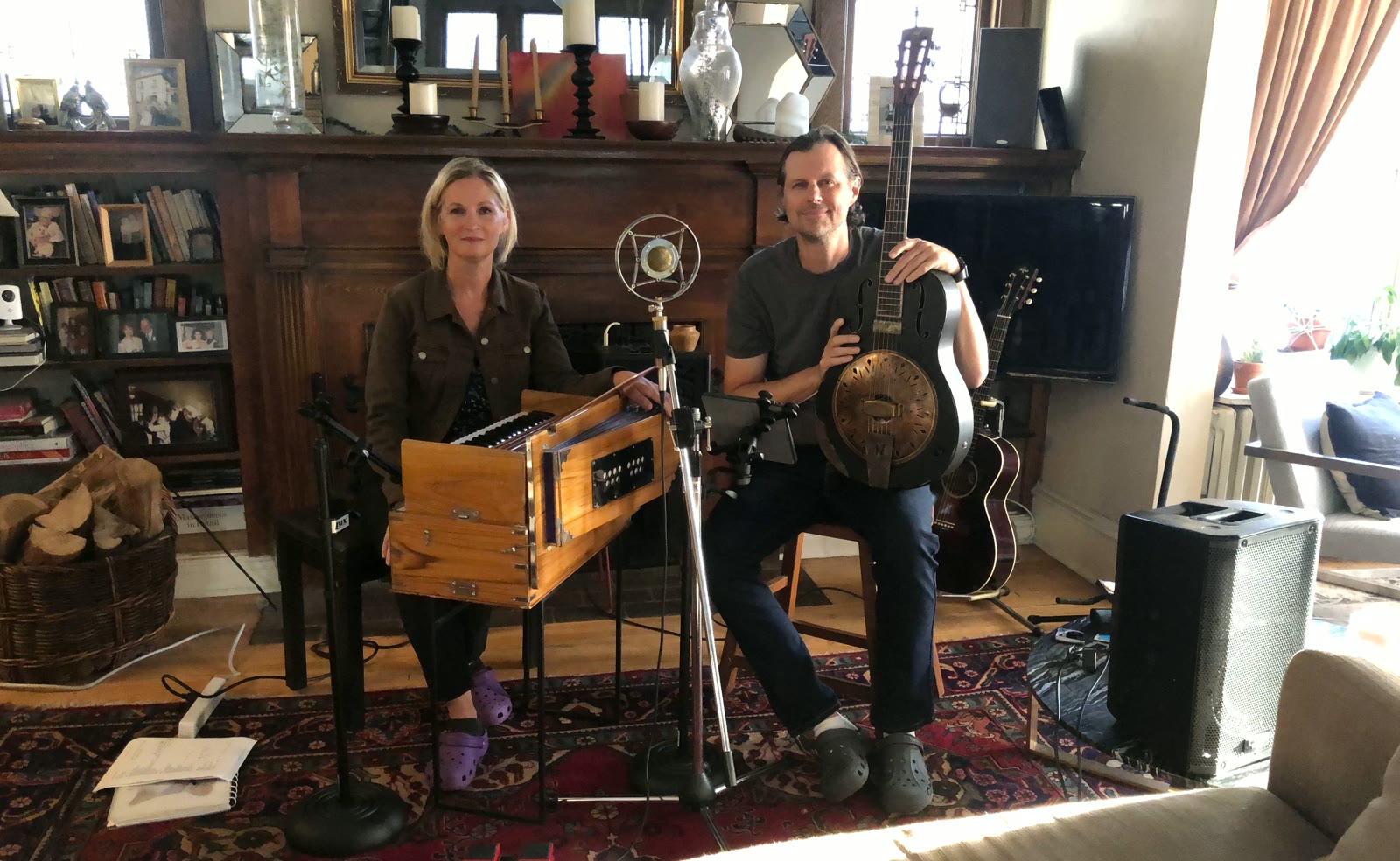 Lisa Hirst and David Carnes of LAND with their instruments in front of the living-room fireplace, Crocs and all
